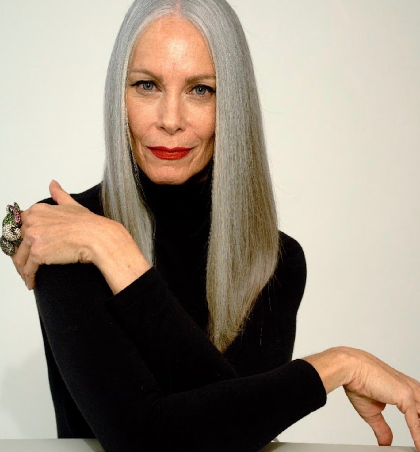 Woman with long gray hair wearing a black top.