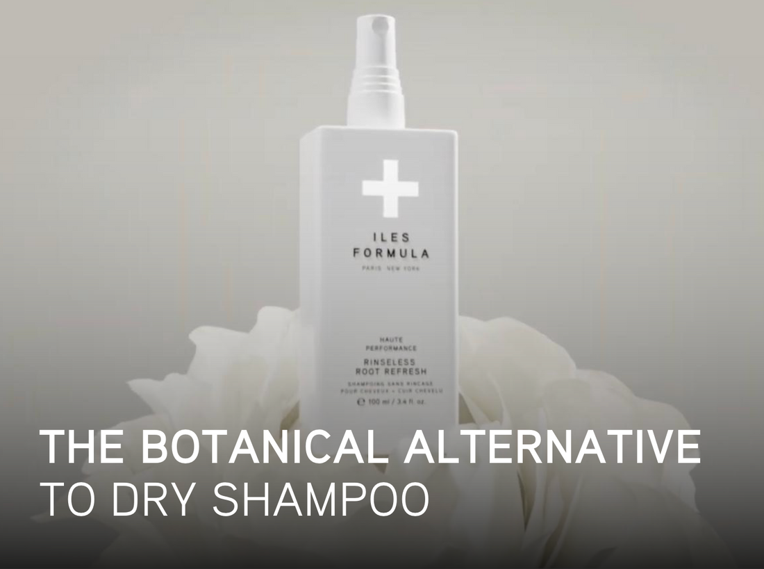White bottle of Iles Formula Rinseless Root Refresh spray displayed among white petals, with text overlay that reads: “The botanical alternative to dry shampoo.”