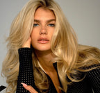 Woman with long, wavy blonde hair wearing a black polka dot shirt.