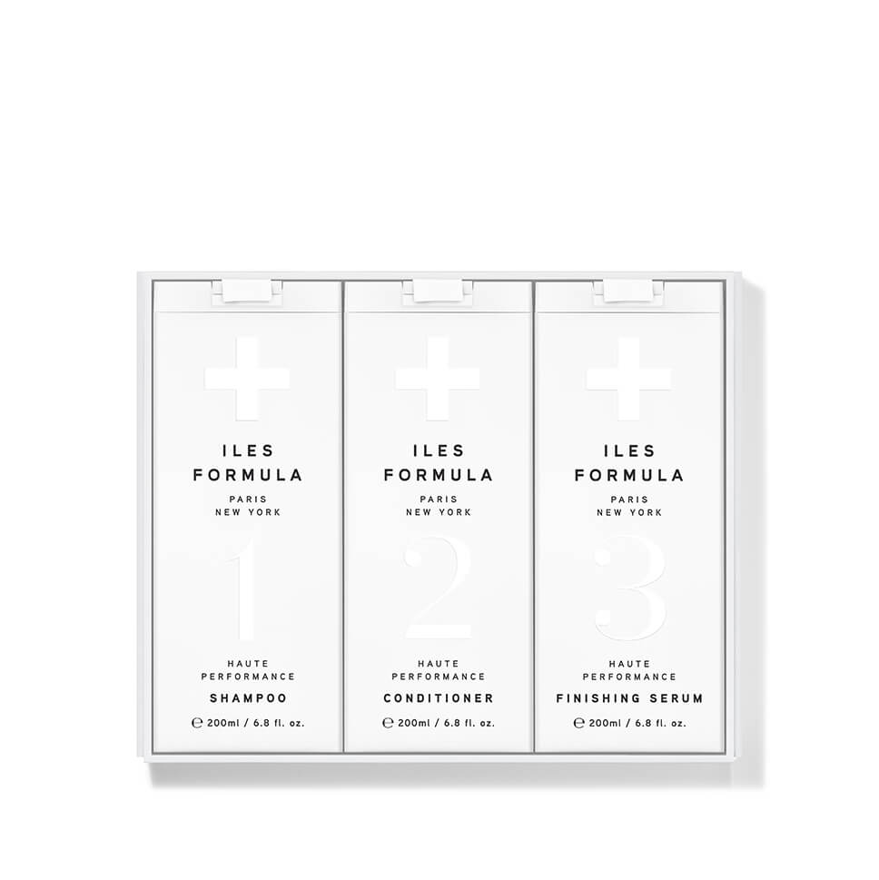 A three-pack of Iles Formula haircare products in a clear plastic case, containing Shampoo, Conditioner, and Finishing Serum. The packaging is white with black text and minimalist cross icons.