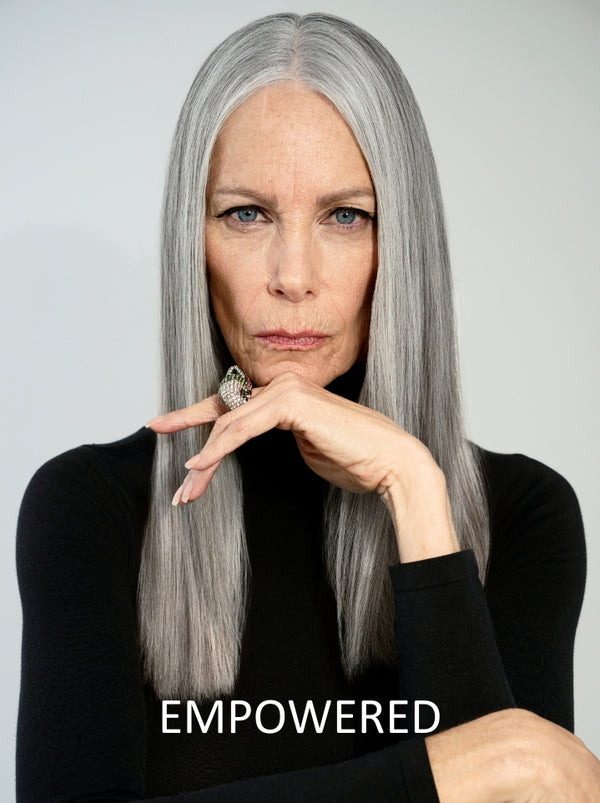 Woman with long gray hair wearing a black top against a gray background with 'EMPOWERED' text.