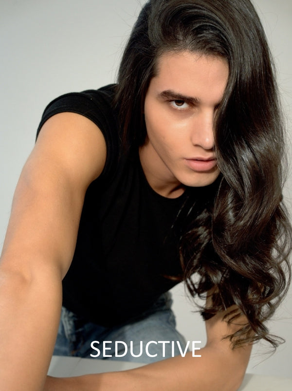 Person with long hair wearing a black sleeveless top on a plain background